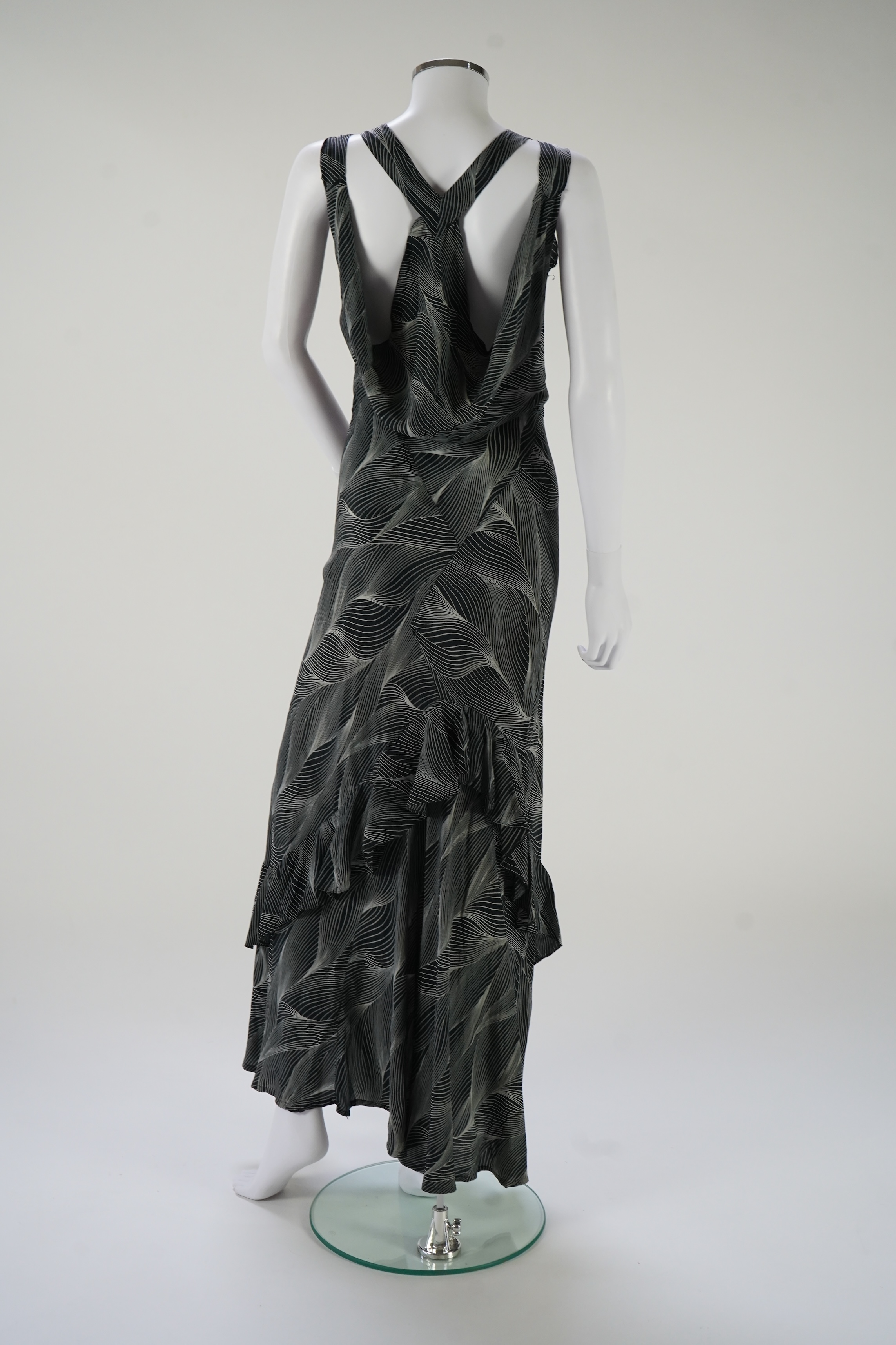 A 1930's black and silver halter neck, bias cut, ladies silk evening dress, designed with a loosely falling back and frills falling from the back of the dress to the front, bust bias cut 32-36 inches, length 57 inches fr